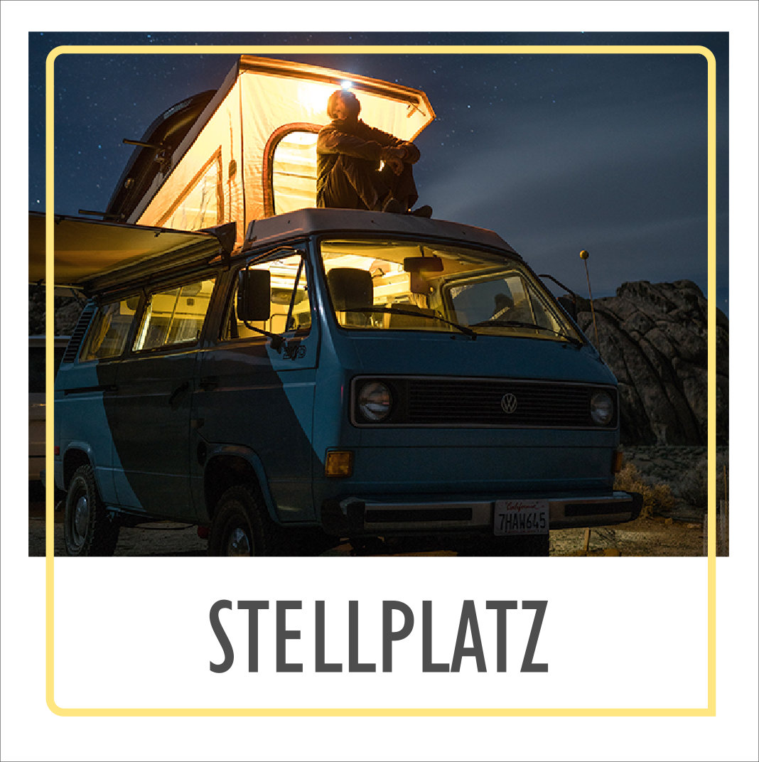 Person sitzt auf Campervan mit beleuchtetem Aufstelldach bei Nacht